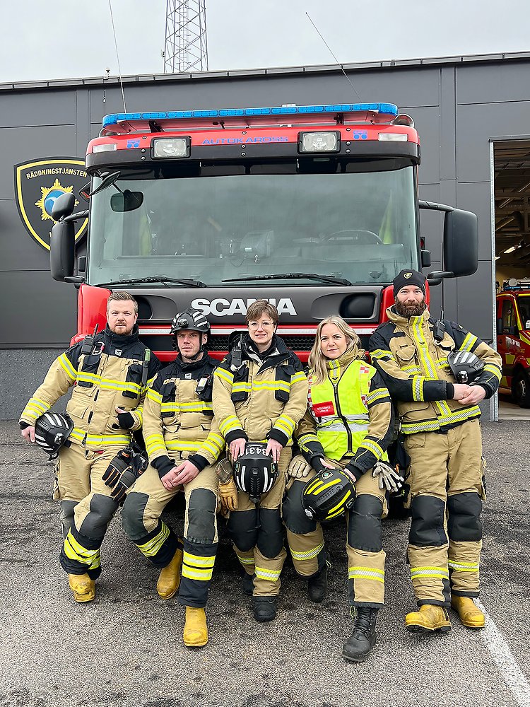 Fem brandmän framför en brandbil.